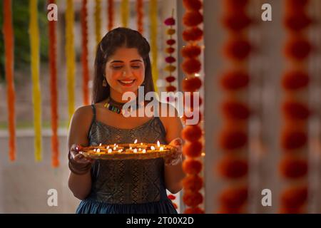 Ritratto di una giovane donna allegra che tiene un piatto di lampade su Diwali Foto Stock