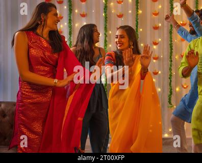Amici che festeggiano Diwali insieme a casa ballando Foto Stock