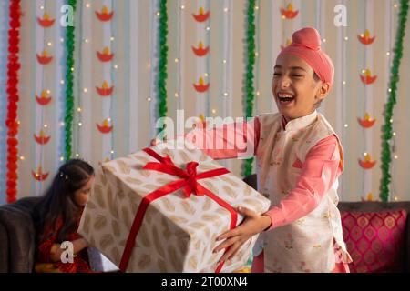 Un ragazzo Sikh sorridente e che offre un regalo in occasione di Diwali Foto Stock