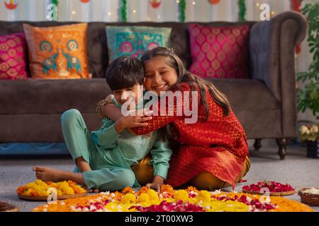Fratello e sorella si divertono decorando il pavimento con fiori (Rangoli) in occasione di Diwali Foto Stock