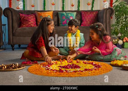 I bambini si divertono mentre decorano il pavimento con fiori ( Rangoli) in occasione di Diwali Foto Stock