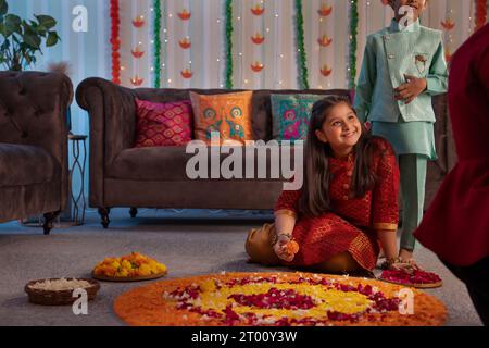 Ragazza in abiti tradizionali che realizza rangoli floreali in occasione di Diwali Foto Stock