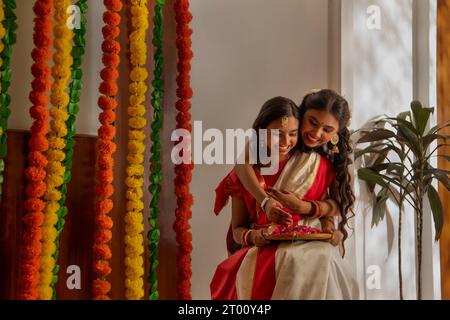 Ritratto di due sorelle bengalesi in una tradizionale casa di decorazione in occasione di Durga Puja Foto Stock