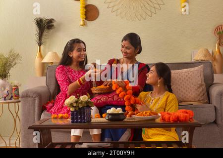 La famiglia bengalese fa la ghirlanda di fiori a casa in occasione della Durga Puja Foto Stock