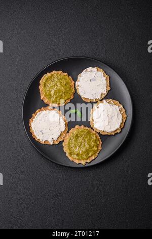 Spuntini rotondi con patatine fritte o cracker croccanti con formaggio cremoso e pesto su un piatto di ceramica Foto Stock