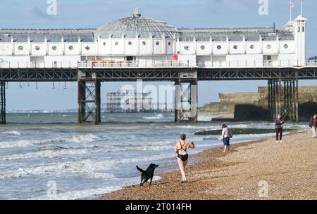 Brighton Regno Unito 3 ottobre 2023 - nuotatori e escursionisti godono di una calda giornata di sole sulla spiaggia di Brighton dato che si prevede che le temperature saranno insolitamente calde per il periodo dell'anno in alcune parti del paese: Credit Simon Dack / Alamy Live News Foto Stock