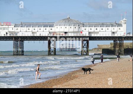 Brighton Regno Unito 3 ottobre 2023 - nuotatori e escursionisti godono di una calda giornata di sole sulla spiaggia di Brighton dato che si prevede che le temperature saranno insolitamente calde per il periodo dell'anno in alcune parti del paese: Credit Simon Dack / Alamy Live News Foto Stock