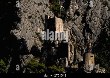 Fortezza medievale di Mirabella o Fortica, nota anche come Peovica, battente bandiera croata, e un bunker della seconda guerra mondiale (probabilmente italiano) sopra la città portuale di Omiš sulla costa adriatica in Dalmazia, Croazia. Foto Stock