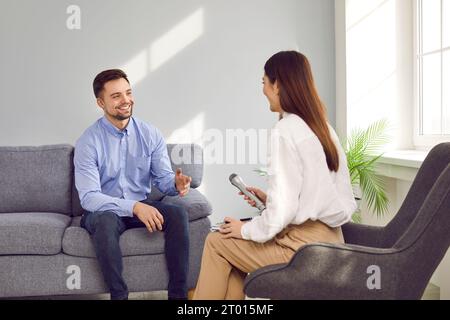 Giovane donna con microfono che intervista sorridente uomo d'affari di successo Foto Stock