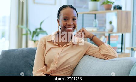 Rilassati, donna nera e ritratto sul divano in casa come proprietario di una casa, investitore immobiliare o acquirente di mutui ipotecari. Sorridi, felice o una persona africana Foto Stock