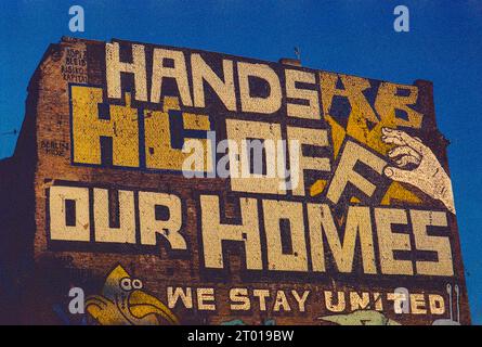 Enorme, attivista: Graffiti 'Hands of Our Homes' sul lato di un edificio domestico a Kopernicker Strasse, berlino, Germania. Mostra un certo attivismo e opposizione nella città verso la gentrificazione del vicinato e l'ascesa dei broker immobiliari che realizzano molti profitti. Immagine ripresa su una vecchia pellicola Kodak analogica. Foto Stock