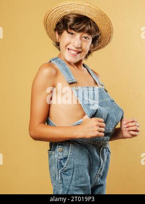 Contadino vestito con salopette e cappello di paglia. E' in un atteggiamento divertente e tiene le sue salopette. Foto Stock