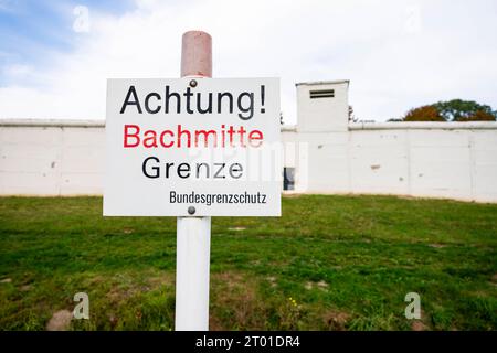TAG DER DEUTSCHEN EINHEIT IM DEUTSCH-DEUTSCHEN MUSEUM MÖDLAREUTH 03/10/2023 - Mödlareuth: Tag der Deutschen Einheit im Deutsch-Deutschen Museum zwischen Bayern und Thüringen in Mödlareuth am 3. Oktober 2023. VOR einem erhaltenen Mauerteil steht ein Schild mit der Aufschrift ãAchtung Bachmitte Grenze ./                   *** GIORNO DELL'UNITÀ TEDESCA NEL MUSEO TEDESCO MÖDLAREUTH 03 10 2023 Mödlareuth giorno dell'unità tedesca nel Museo tedesco tedesco tra Baviera e Turingia a Mödlareuth il 3 ottobre 2023 di fronte a una parte conservata del muro c'è un cartello con l'iscrizione ãAchtung B Foto Stock