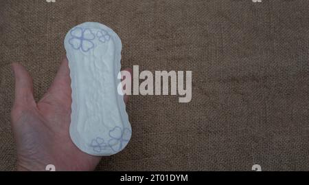 Tamponi igienici da donna su sfondo marrone. Donna che tiene la mano ogni giorno. concetto di igiene Foto Stock