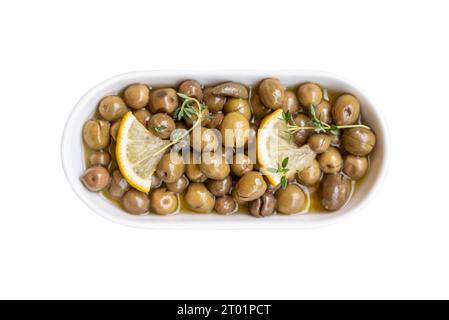 Olive verdi su un piatto di porcellana bianca su sfondo bianco Foto Stock