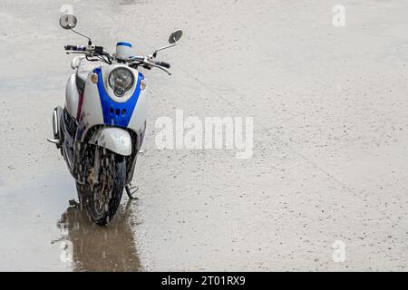 Motocicletta parcheggiata per strada in caso di forte pioggia Foto Stock