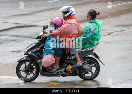 SAMUT PRAKAN, TAILANDIA, 20 settembre 2023, Una famiglia vestita di impermeabili sta cavalcando una moto sotto la pioggia Foto Stock