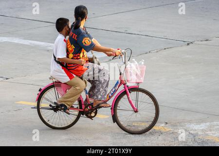 SAMUT PRAKAN, THAILANDIA, 25 2023 settembre, Una donna cavalca un ragazzo in bicicletta Foto Stock