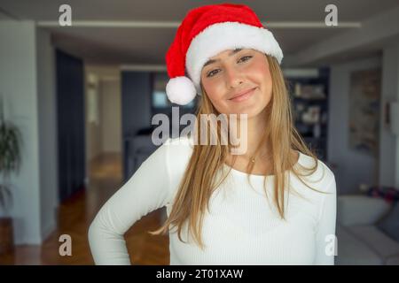 Giovane donna che indossa il cappello di babbo natale a casa Foto Stock