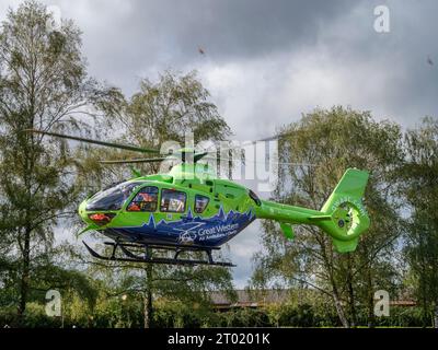 La Great Western Air Ambulance parte dall'esterno del Gloucester Royal Hospital. Il luminoso elicottero verde lime e blu, segnale di chiamata Helimed 65, è Foto Stock