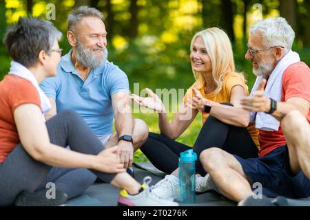 Gruppo di Happy Seniors che riposano insieme dopo l'allenamento fitness nel parco Foto Stock