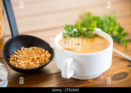 Zuppa di purea di piselli secchi cotta con funghi in una ciotola su un tavolo di legno scuro. Foto Stock