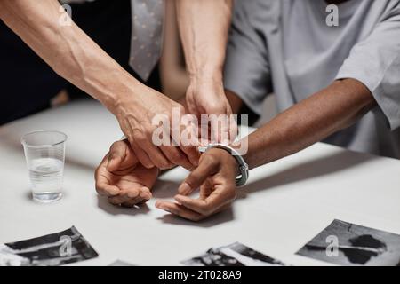 Primo piano dell'agente di polizia che mette le manette sul sospetto durante le indagini, spazio per le copie Foto Stock