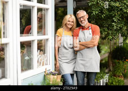 Coppia di contadini in età matura che indossa grembiuli in posa insieme al Terrace Outdoors Foto Stock