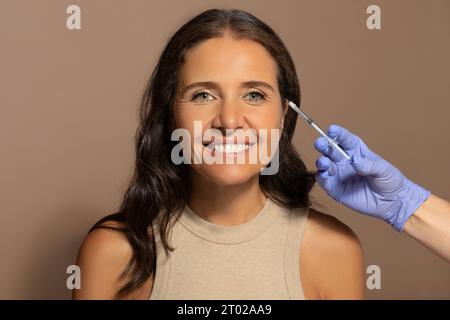 Estetista in guanti fa iniezione a donna anziana caucasica sorridente Foto Stock