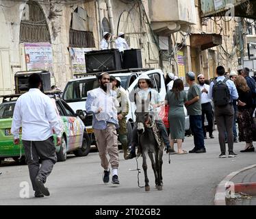 Hebron, Cisgiordania. 3 ottobre 2023. Un ragazzo ebreo cavalca un asino davanti a negozi palestinesi chiusi durante il festival ebraico di Sukkot, la festa dei Tabernacoli, a Hebron, Cisgiordania, martedì 3 ottobre, 2023. foto di Debbie Hill/ Credit: UPI/Alamy Live News Foto Stock