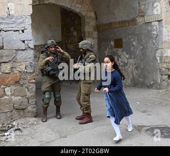 Hebron, Cisgiordania. 3 ottobre 2023. Una ragazza israeliana corre davanti ai soldati israeliani durante il festival ebraico di Sukkot, la festa dei Tabernacoli, a Hebron, in Cisgiordania, martedì 3 ottobre, 2023. foto di Debbie Hill/ Credit: UPI/Alamy Live News Foto Stock