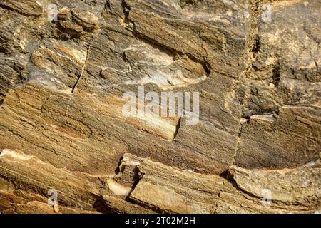 Sfondo di rocce marroni a strati grossolani, telaio completo. Consistenza ruvida in pietra delle montagne. Geologia e alpinismo a tema. Copia spazio. Foto Stock