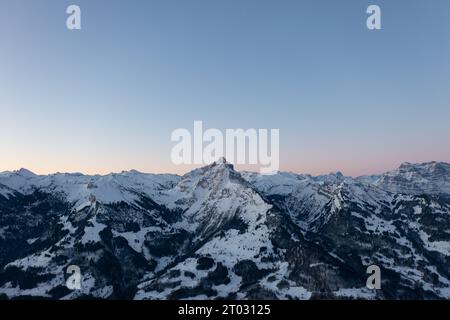 Foto di un drone nelle Alpi svizzere su un lago chiamato Walensee e sullo sfondo le vette delle montagne sono illuminate dal sole del mattino. Foto Stock