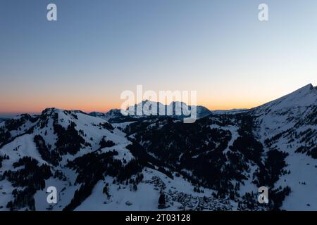 Foto di un drone nelle Alpi svizzere su un lago chiamato Walensee e sullo sfondo le vette delle montagne sono illuminate dal sole del mattino. Foto Stock