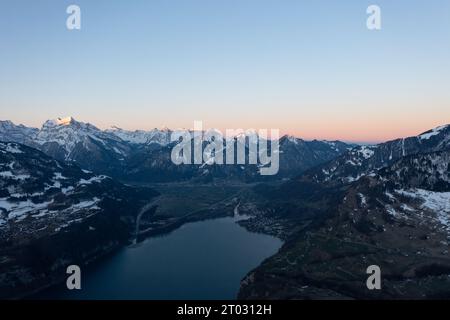 Incredibile alba con un orizzonte rosa sulle cime delle Alpi svizzere sopra un lago di montagna nel Canton Glarona. Foto Stock