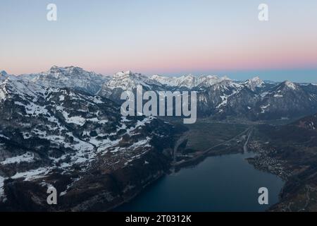 Incredibile alba con un orizzonte rosa sulle cime delle Alpi svizzere sopra un lago di montagna nel Canton Glarona. Foto Stock