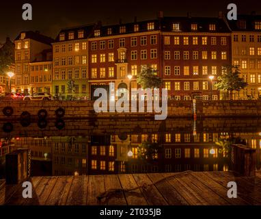 Molo di legno vicino al canale Slotsholm a Copenaghen, dove le case si riflettono nell'acqua calma di notte, Danimarca, 2 ottobre 2023 Foto Stock