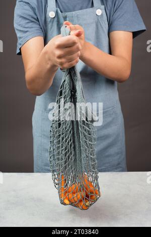 Tenere le carote fresche in un sacchetto riutilizzabile in rete, verdure dal mercato, cibo sano e zero sprechi Foto Stock