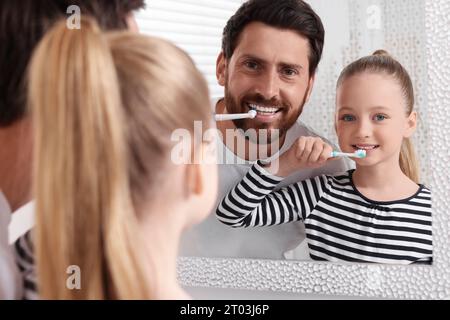 Padre e sua figlia lavano i denti insieme vicino allo specchio in casa Foto Stock