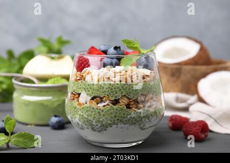 Gustosa farinata d'avena con budino di chia matcha e frutti di bosco su un tavolo di legno nero, primo piano. Colazione salutare Foto Stock