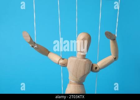Un burattino di legno con corde su sfondo blu chiaro Foto Stock
