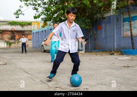 La città di HO CHI MINH, VIETNAM - 31 Ottobre 2016: ragazzi vietnamiti a giocare il gioco del calcio di fronte all edificio scolastico nella città di Ho Chi Minh, Vietnam. Foto Stock