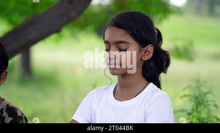 Incantevole bambina che fa una seria meditazione yoga in giardino. Piccola ragazza indiana che fa meditazione Foto Stock