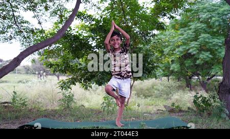 Ritratto di un bellissimo ragazzo che pratica yoga all'aperto. I bambini possono praticare yoga asana o esercizi ginnici. Bambini piccoli che meditano nel lotus po Foto Stock