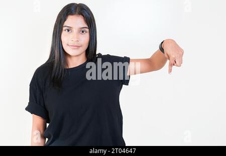 Ragazza allegra che punta la pubblicità verso il basso. Sorridente ragazza latina che indica una pubblicità. Persone latine che puntano verso il basso uno striscione Foto Stock