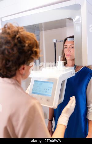 Foto verticale della vista posteriore di un dentista che utilizza una macchina odontoiatrica a raggi X con un paziente Foto Stock