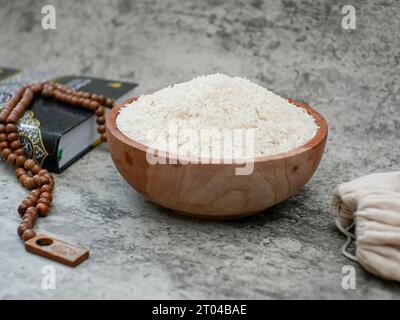 sacro Corano e un chicco di riso in una ciotola di legno. Concetto di zakat islamico Foto Stock