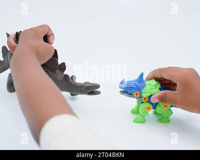 le mani dei bambini giocano a stegosaurus e centrosaurus, genere di dinosauro corazzato isolato su sfondo bianco Foto Stock