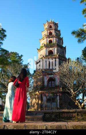 Vietnam: Donne in vietnamita tradizionale ao dai ("abito lungo"), Thien Mu Pagoda, Hue. La Pagoda di Thien Mu fu costruita nel 1601 sotto Nguyen Hoang, il governatore della provincia di Thuan Hoa, ora nota come Hue. Anche se giurò fedeltà alla dinastia le ad Hanoi, Nguyen Hoang governò effettivamente Thuan Hoa come stato indipendente nel Vietnam centrale. La pagoda ha sette storie ed è la più alta del Vietnam, ed è spesso oggetto di rime popolari e poesie su Hue, che fu la capitale imperiale del Vietnam tra il 1802 e il 1945. Foto Stock
