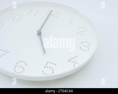 l'orologio bianco a parete mostra l'ora alle 5 o alle pm su sfondo bianco Foto Stock